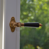 Antiker Messing Fenstergriff mit schwarzer Griffhülse an weißem Fenster